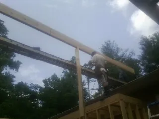 Carpenter setting a ridge beam over a new addition frame — Ice Dam Removal by Roofing Brothers in Saint Hilaire