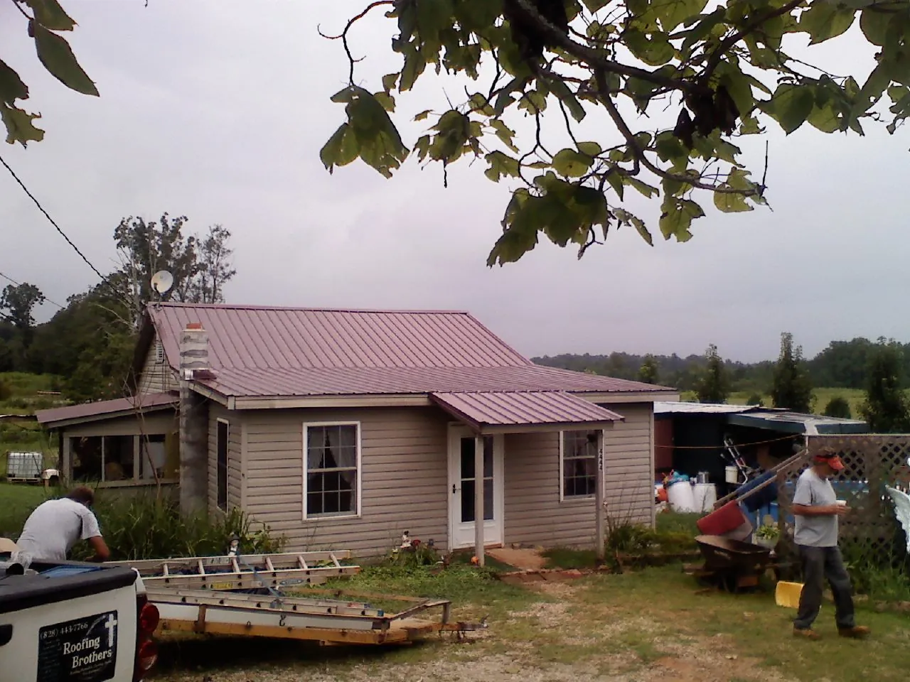 Crew finishing a mauve metal roof on a small farmhouse in Saint Hilaire