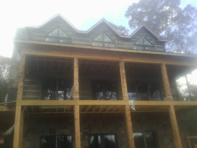 Dormers and porch framing on a large log home under construction — Roof Coating work by our crew in Saint Hilaire