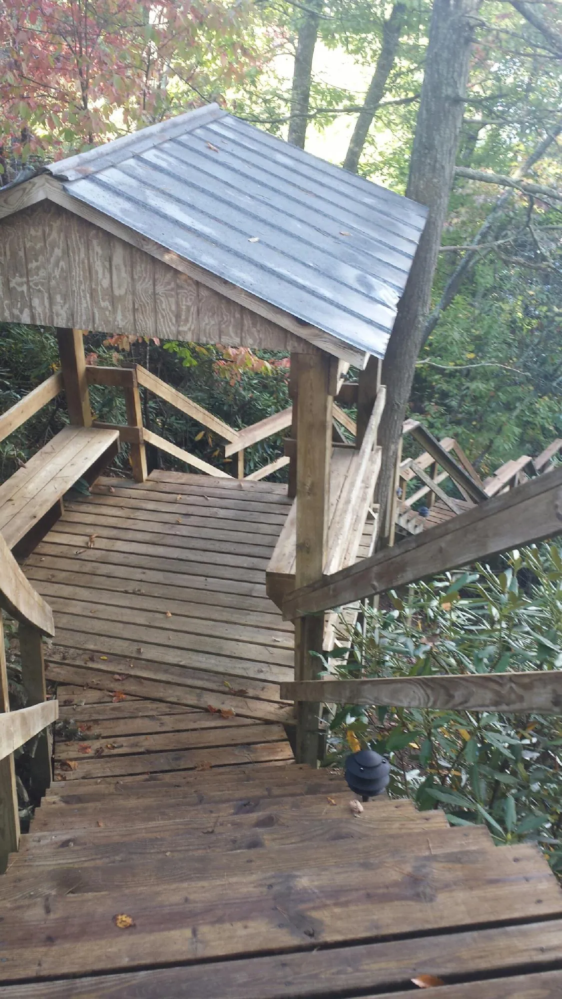 Metal roofed shelter over wooden steps on a wooded walkway — Skylight Repair & Installation work by our crew in Saint Hilaire