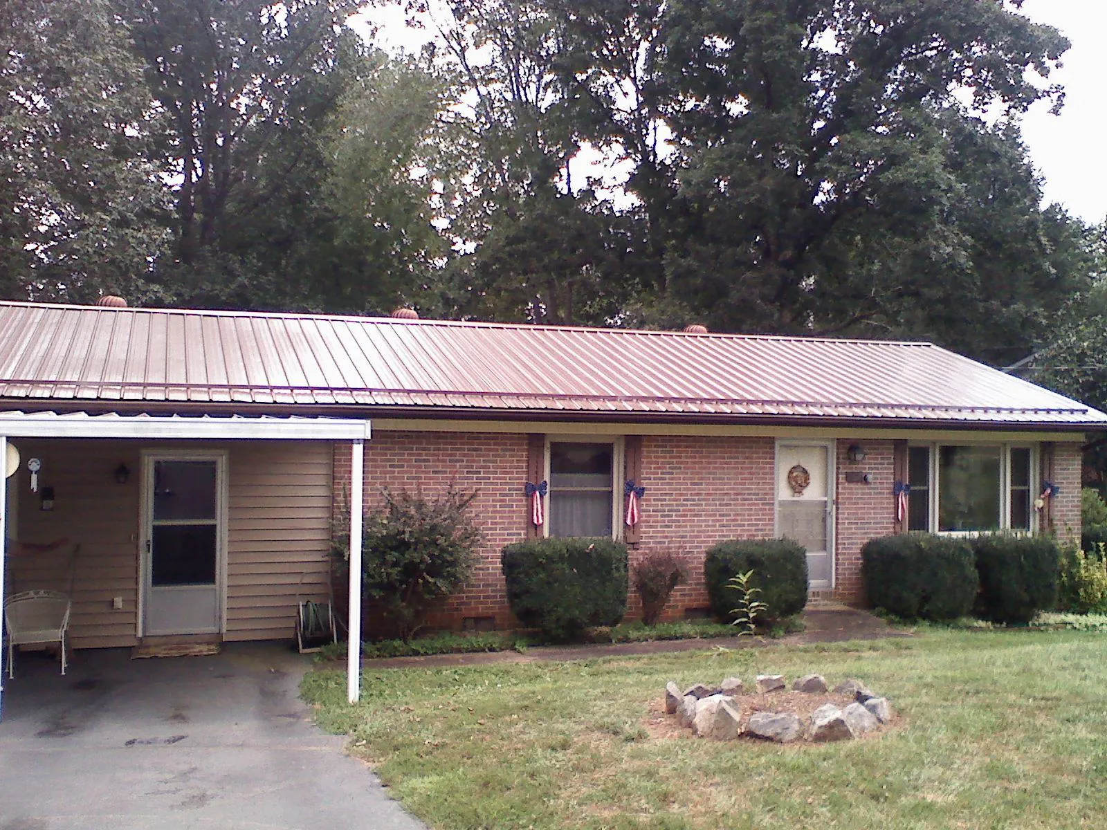 Bronze metal roof and carport on a brick ranch home — Roof Repair work by our crew in Saint Hilaire