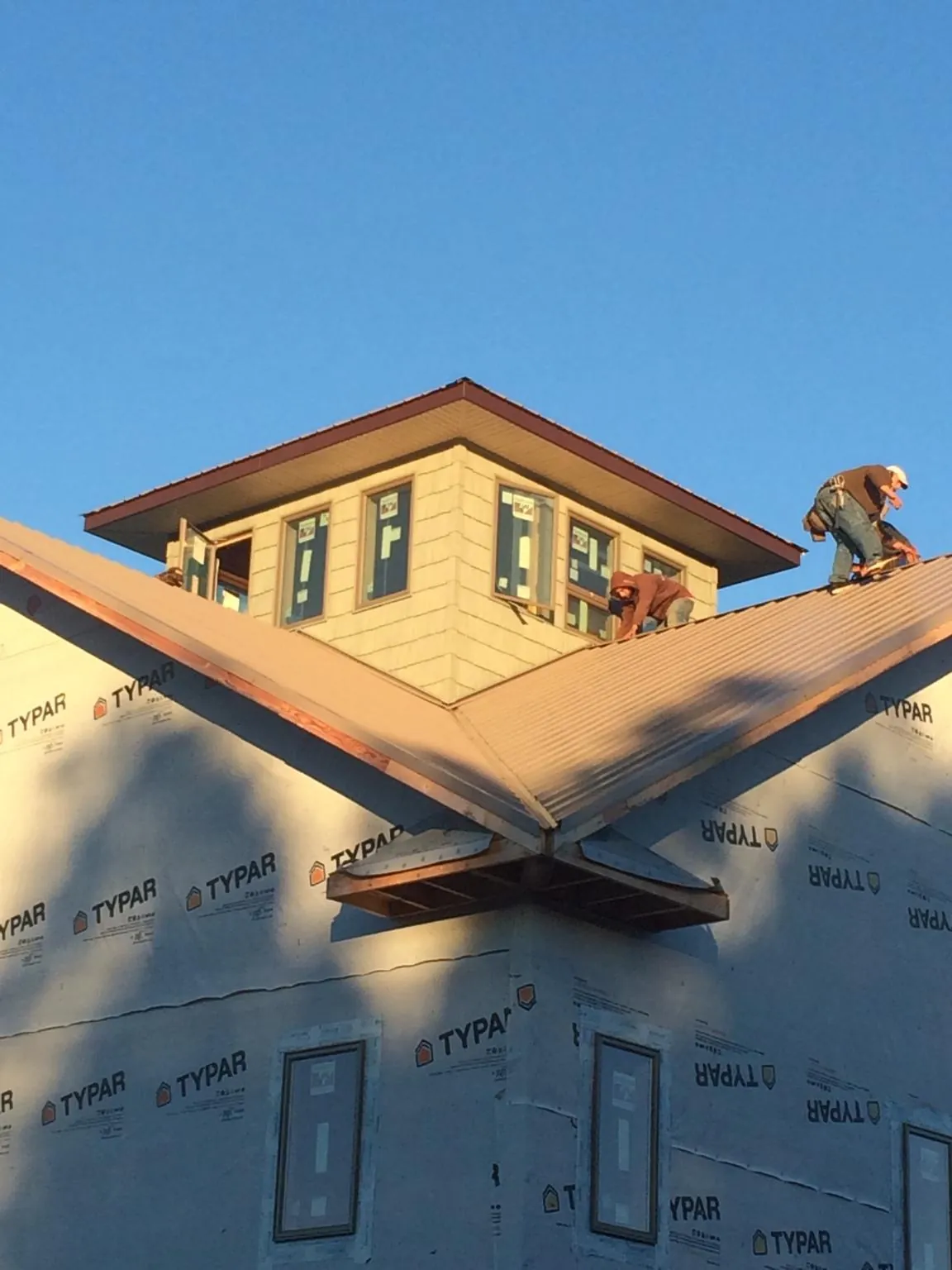 Roofers working around a rooftop cupola on a new metal roof at sunset — Roof Waterproofing in Saint Hilaire by Roofing Brothers